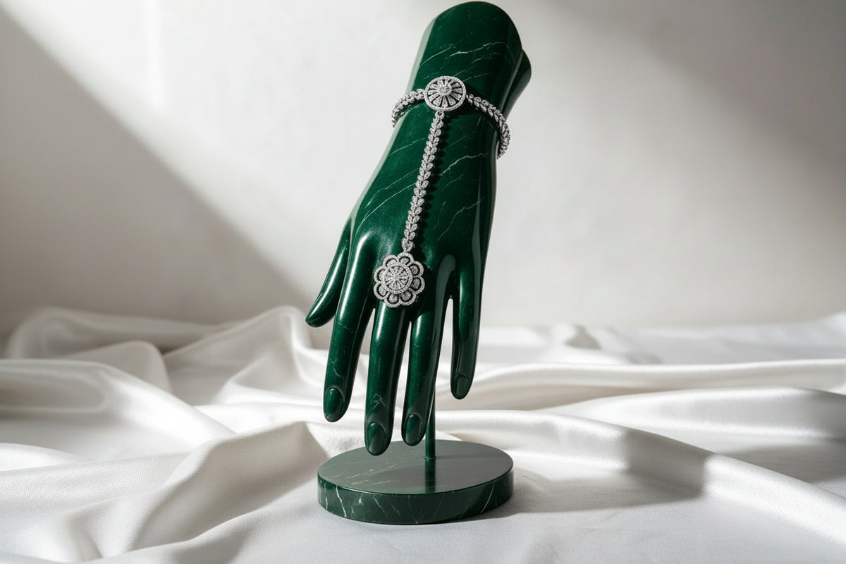 Silver plated floral AD stone hathphool hand harness — sparkling CZ stone bracelet connected to ring, displayed on black marble hand stand, premium Pakistani bridal festive jewelry.