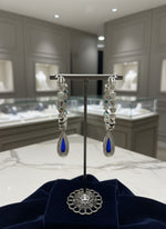 Silver earrings with blue stones on a stand in a jewelry store setting