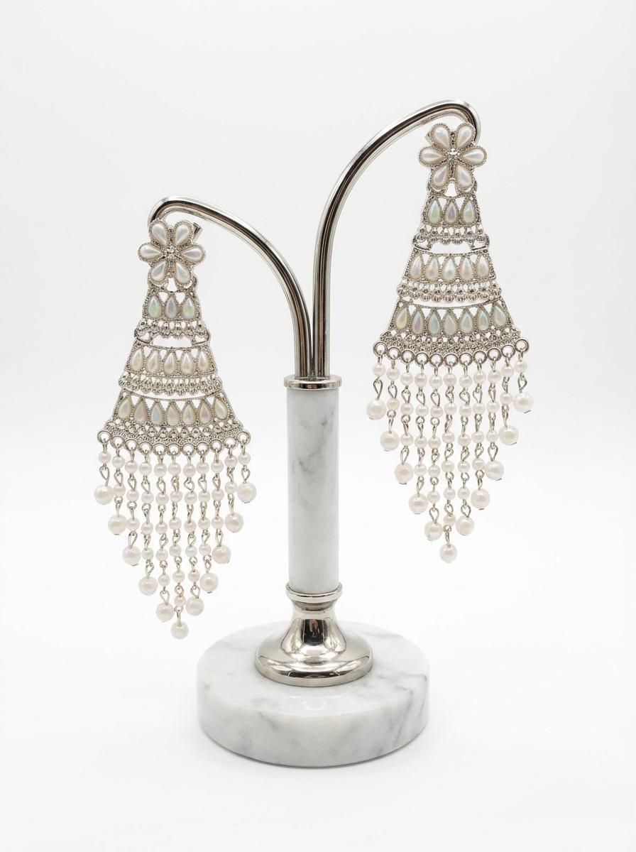 Silver filigree work and iridescent teardrop accents on elegant pearl statement earrings on stand.