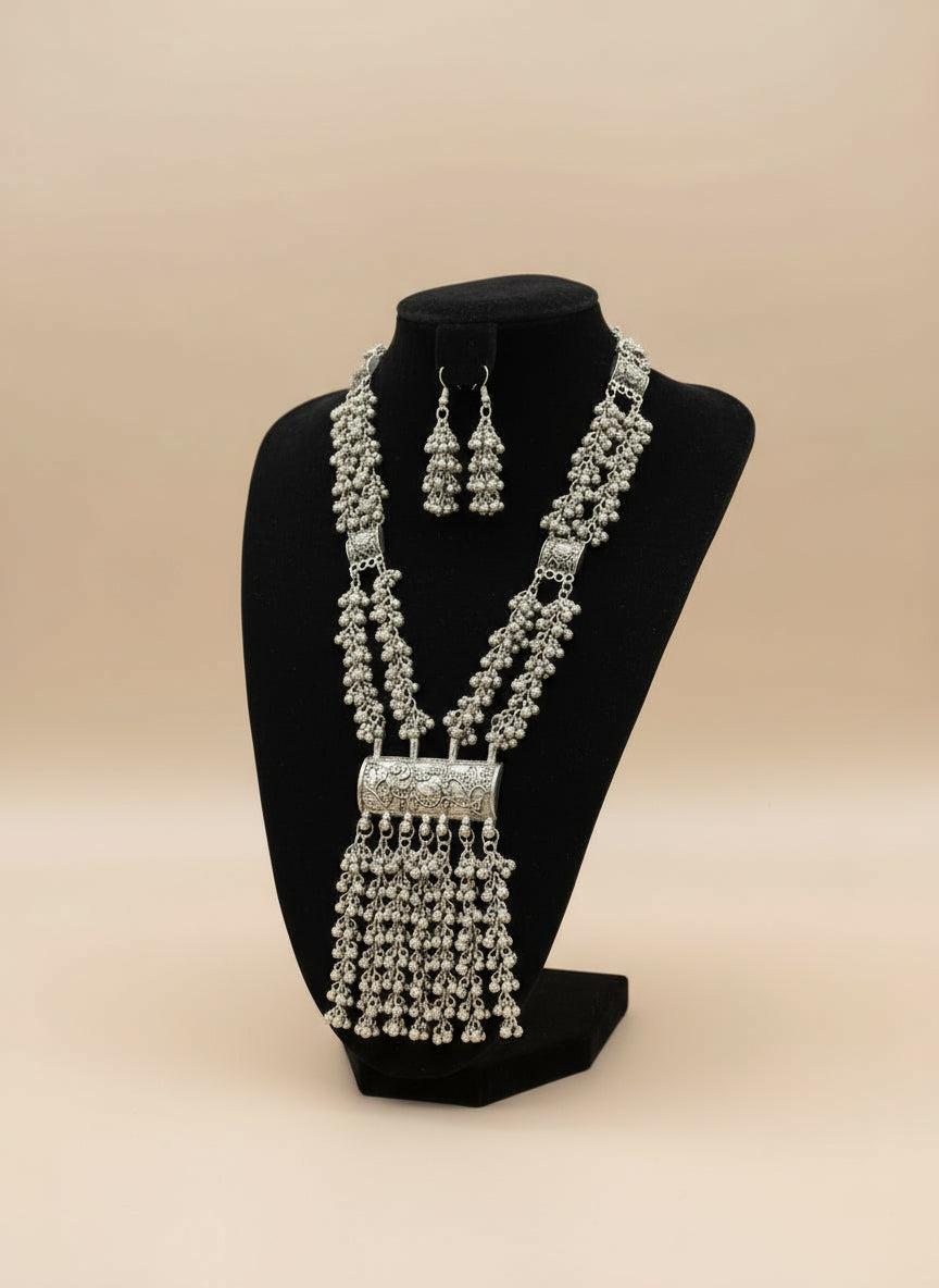 Oxidised long necklace and drop earrings on a black dummy with a blurred background