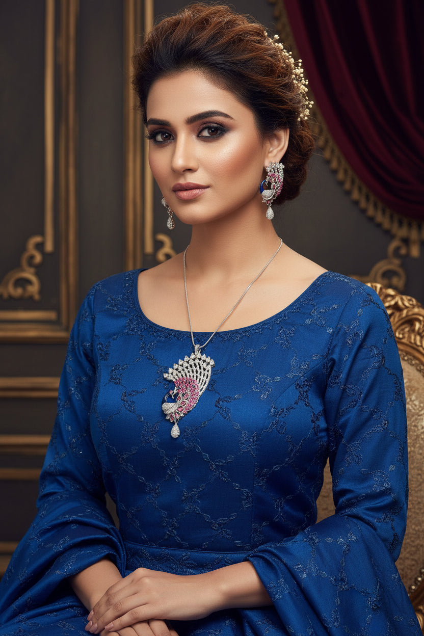 Silver plated a set of peacock-shaped pendant in silver chain with peacock-shaped earrings. The pendant is detailed with blue enamel and has sparkling crystal white AD and hot pink stones embellishments. Party wear jewellery set. Jewellery set is displayed on a black velvet jewellery dummy.