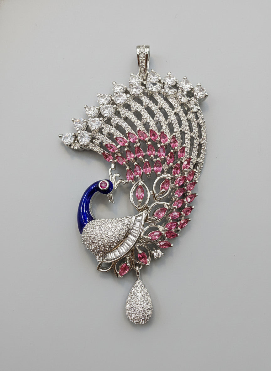 Silver plated peacock-shaped pendant in Silver chain The pendant is detailed with blue enamel and has sparkling white and pink AD crystal embellishments. Pendant is focused to show the details and design of this pendant.