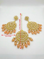  Sophisticated peach and rose gold ethnic earrings paired with a coordinating traditional outfit.