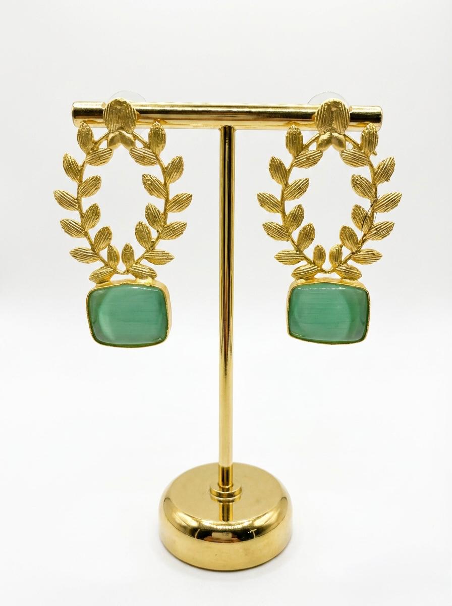 Statement earrings featuring an emerald green sugar stone with detailed floral carvings and golden accents.