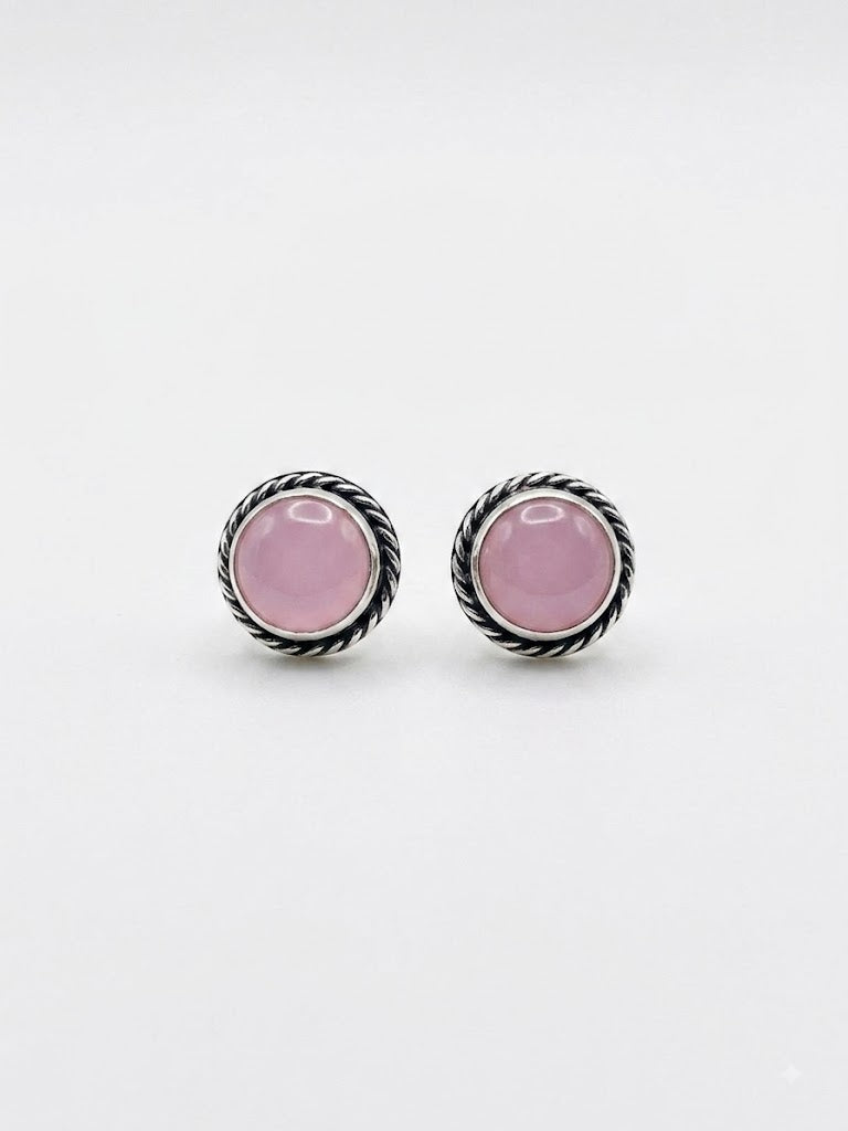 A pair of silver-toned twisted rope stud earrings with oval pink cabochon gemstones, displayed on a clean white background.