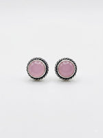 A pair of silver-toned twisted rope stud earrings with oval pink cabochon gemstones, displayed on a clean white background.