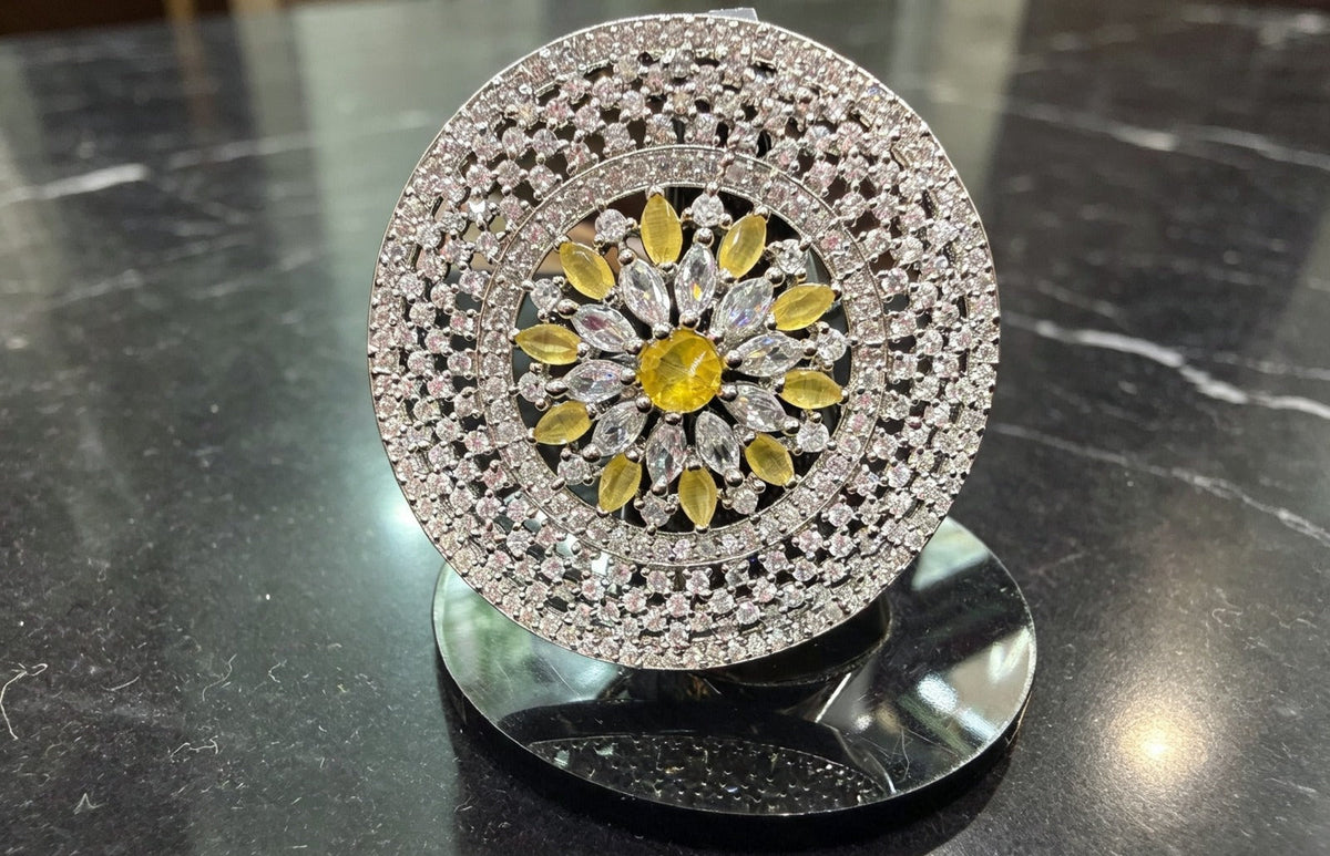 Sunflower Splendor Diamond Statement Ring by Famaza Couture — Fancy Yellow center stone with marquise and pear-cut white diamonds, displayed on stand against black marble surface, luxury floral halo cocktail ring.
