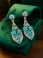 A pair of teal petal chandelier earrings displayed on a green stand as shown in image.