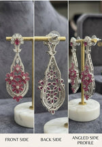 Close-up technical view of the reverse side of a ruby and diamond earring, displaying the detailed white gold filigree work and precision basket settings for the gemstones.