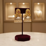 TheGold stud with oxidised dome in the bottom and nano pearls double line hanging pearls jhumka earrings and pearl earrings on display in a jewellery store with 'Famaza Couture branding.