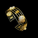 Gold bracelet with leaf-shaped stones on a black background
