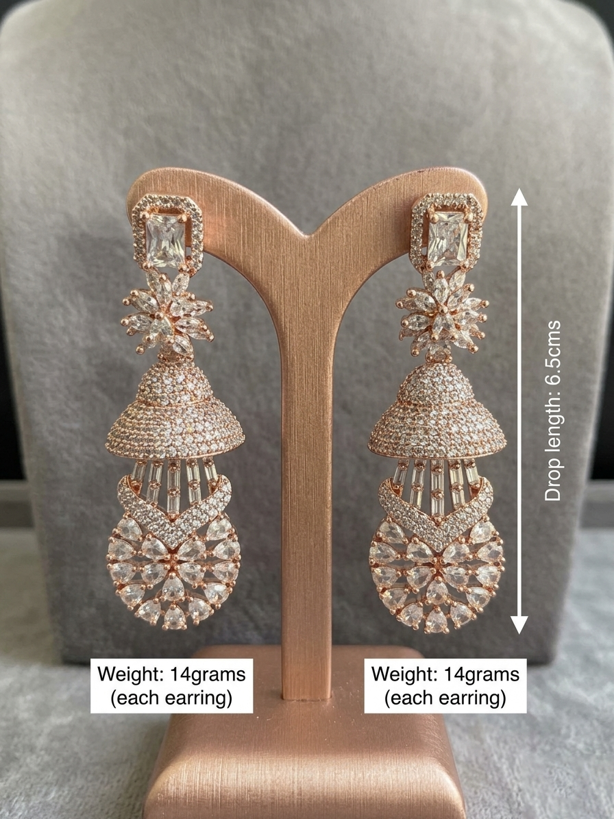 A pair of luxury rose gold multi-tier Jhumka chandelier earrings displayed on a matching rose gold T-bar stand, featuring an emerald-cut crystal top stud, a marquise floral star link, a micro-pave dome, and a lower teardrop lattice medallion.