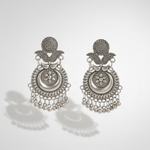 A pair of ornate silver-toned traditional earrings with intricate filigree, circular medallions, and dangling bead chains, displayed on a light gray background with soft shadows.
