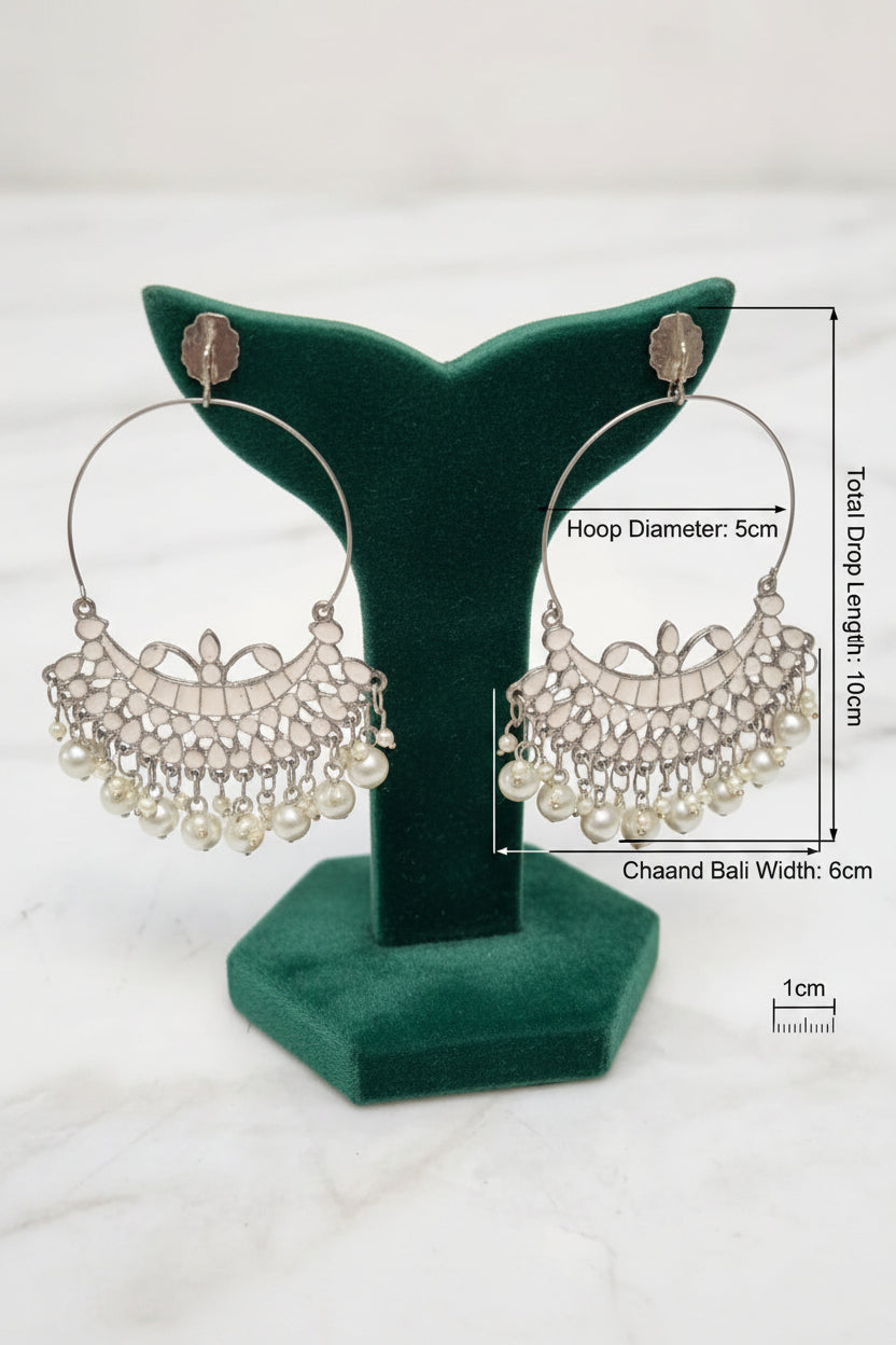 Traditional silver Chaand Bali statement earrings with large upper hoops and hanging white pearl drops on a display stand.