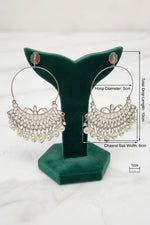 Traditional silver Chaand Bali statement earrings with large upper hoops and hanging white pearl drops on a display stand.