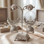 The Silver earrings with pearl accents held by a hand against a blurred natural background