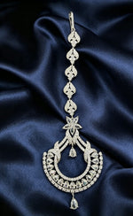 he Siya Regal Star & Crescent Luxe Cubic Zirconia Maang Tikka — silver-toned, cascading petal links, star motif, pear & round cut CZ stones, double teardrop drops, intricate crescent frame, premium bridal forehead jewelry against deep navy satin.