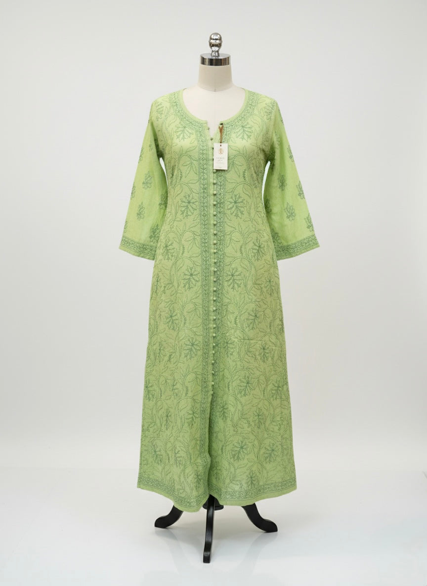 Theapple green dress with floral patterns on a grey surface with small decorative items.