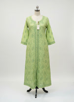 Theapple green dress with floral patterns on a grey surface with small decorative items.