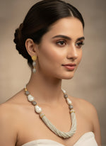 A black mannequin showcasing a Bollywood style grey colour Mona Lisa stone and grey colour nano crystal beaded Mala set, withgrey colour mona lisa stone and gold-tone accents. 