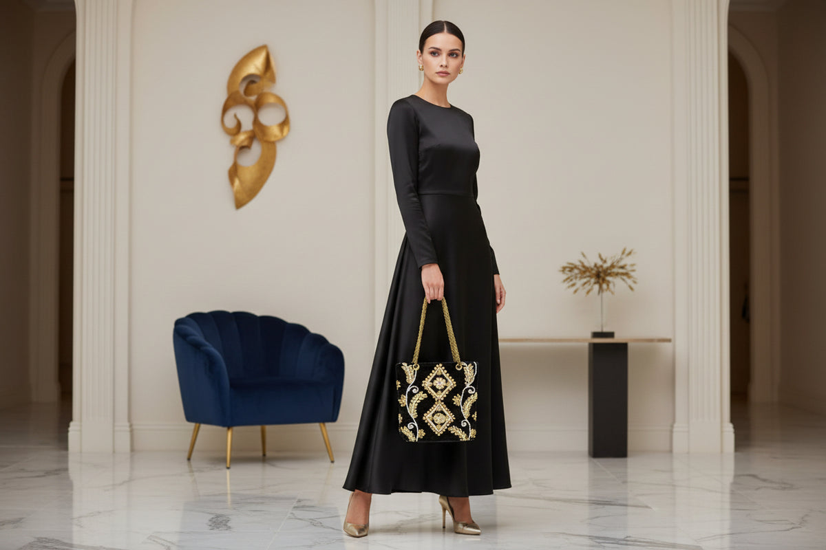 The black velvet tote bag with gold and white floral hand embroidery and beaded details. The handles are shown on the front. 