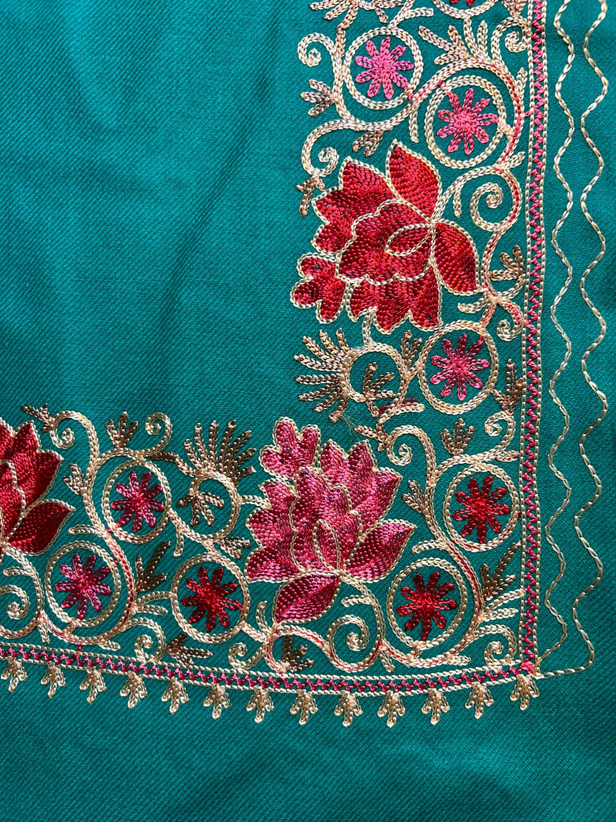 The blue pashmina scarf with detailed floral embroidery and tassels on the ends.