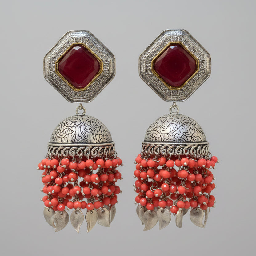 The earrings carries the redstone in the top stud and carrot red hangings underneath the Jhumkey dome and nano oxidised hanging in in the last.