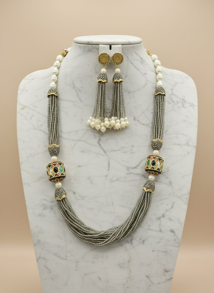 The luxurious Tanjore Art Meenakari grey beaded Mala Set featuring a bridal pearl necklace with accompanying earrings, predominantly in gold and white colours with ornate designs.