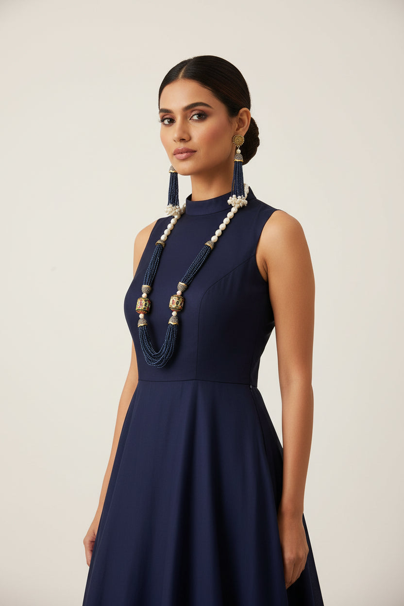 The luxurious Tanjore Art Meenakari navy blue beaded Mala Set featuring a bridal pearl necklace with accompanying earrings, predominantly in gold and white colours with ornate designs.