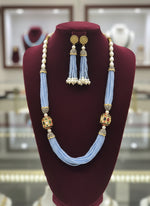 The luxurious Tanjore Art Meenakari sky blue beaded Mala Set featuring a bridal pearl necklace with accompanying earrings, predominantly in gold and white colours with ornate designs.