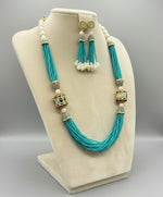 The luxurious Tanjore Art Meenakari turquoise beaded Mala Set featuring a bridal pearl necklace with accompanying earrings, predominantly in gold and white colours with ornate designs. 