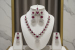 The mannequin showcasing a necklace set with ruby pink and white ad stones, accompanied by earrings and a maang tikka. Party wear set. 