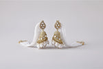 The pair of a woman wearing a white beaded earring with rose gold accents jhumkey.