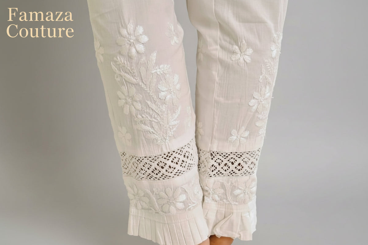 The rear view close-up of white embroidered cotton pants with pockets, showing the texture and design details. 