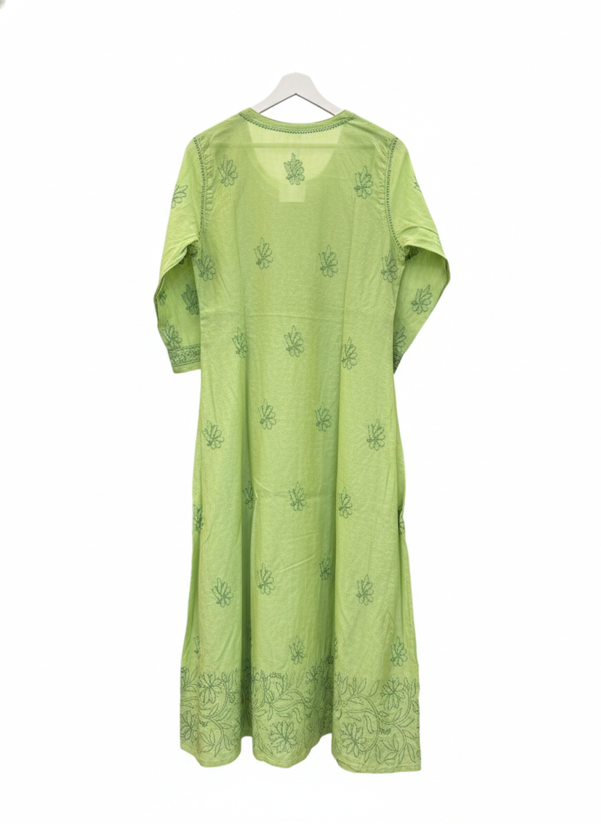 The rear view ofapple green dress with floral patterns on a grey surface with small decorative items.
