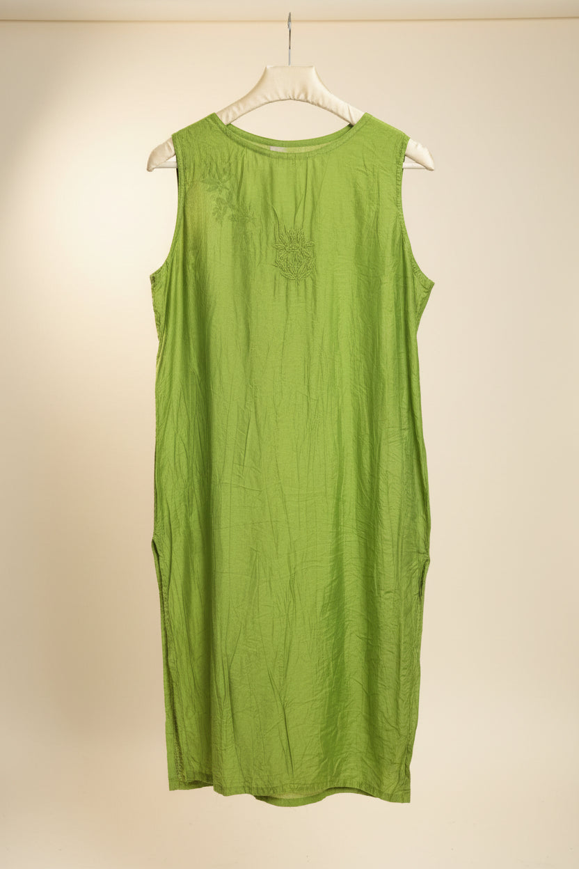 The rear view of this lime green sleeveless tunic top with a subtle embroidered motif on the top chest, hanging on a white hanger in a cluttered closet or retail environment.
