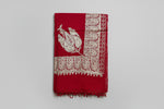 The red colour Kashmiri embroidered pashmina shawl with tassels on the ends, displayed on a wooden surface.