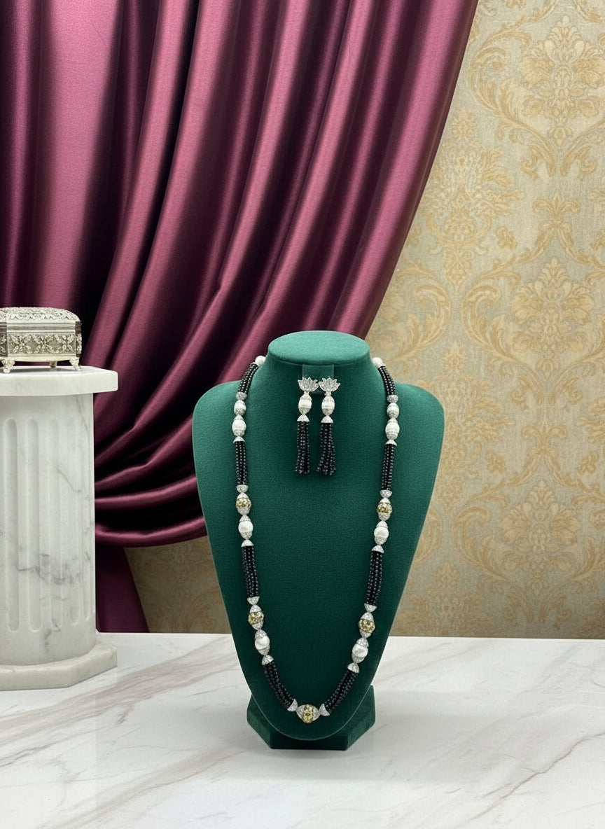 The set of jewellery featuring a long necklace with black-coloured glass beads and metallic accents, paired with matching earrings, displayed on a mannequin bust. 