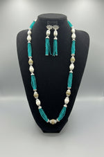 The set of jewellery featuring a long necklace with sky blue-coloured glass beads and metallic accents, paired with matching earrings, displayed on a mannequin bust. 