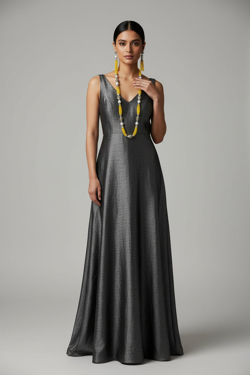 The set of jewellery featuring a long necklace with yellow-coloured glass beads and metallic accents, paired with matching earrings, displayed on a mannequin bust. Party wear set. 