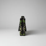 The side view of a black floral handcrafted tote bag with glass beads embroidered on a white silk base, displayed on a wooden surface with a greenery background