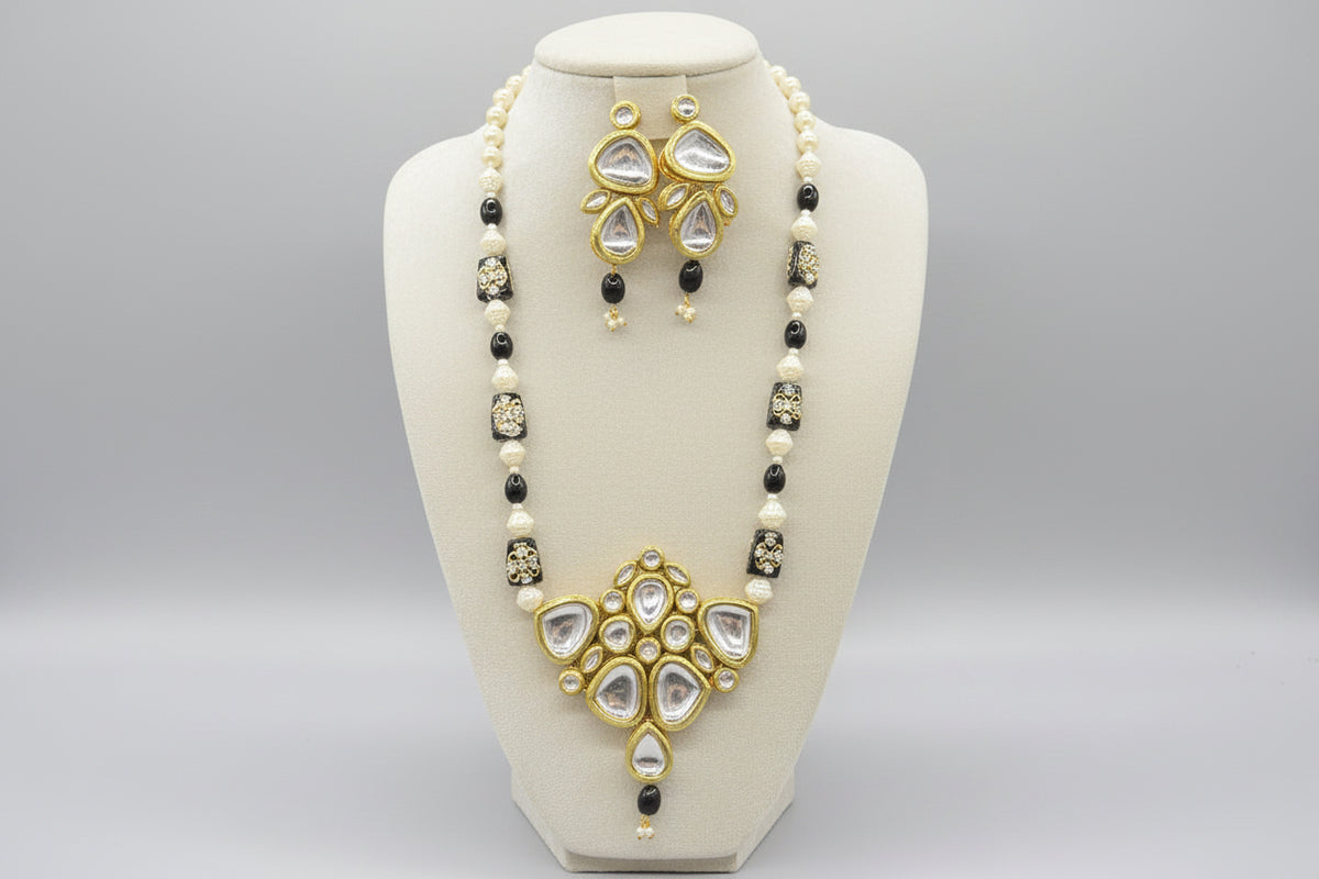 The traditional bridal necklace set displayed on a mannequin, featuring black and gold colours with intricate detailing and pearl beads. Party wear set. 