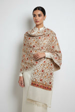 The white base colour Kashmiri embroidered pashmina scarf with maple leaf motifs and tassels on the ends, displayed on a wooden surface.