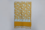 This orange Kashmiri embroideredpashmina scarf with white floral patterns and tassels on the ends, displayed against a golden background.
