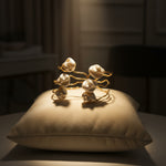Top-down view of two Mother of Pearl inlay gold bracelets displayed on a soft grey silk cushion, highlighting the natural shell texture and gold shine.