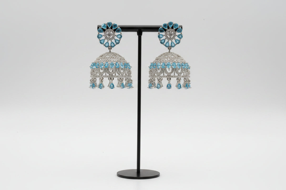 Traditional silver-toned jhumka earrings adorned with shimmering ice blue stones and delicate hanging crystal beads.