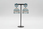 Traditional silver-toned jhumka earrings adorned with shimmering ice blue stones and delicate hanging crystal beads.