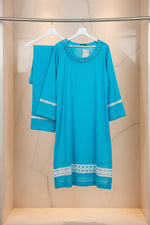 Turquoise Pakistani kurti and trousers are hanging in the image. 