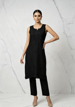 A model wearing the black handcrafted sleeveless Chanderi silk Chikankari co-ord set, posing against a white marble studio background.