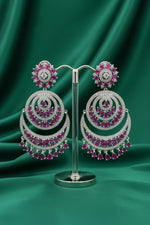 A pair of Royal Fuchsia Crescent Statement Dangle Earrings displayed on a stand, showcasing intricate silver-tone metalwork with vibrant fuchsia stone embellishments.